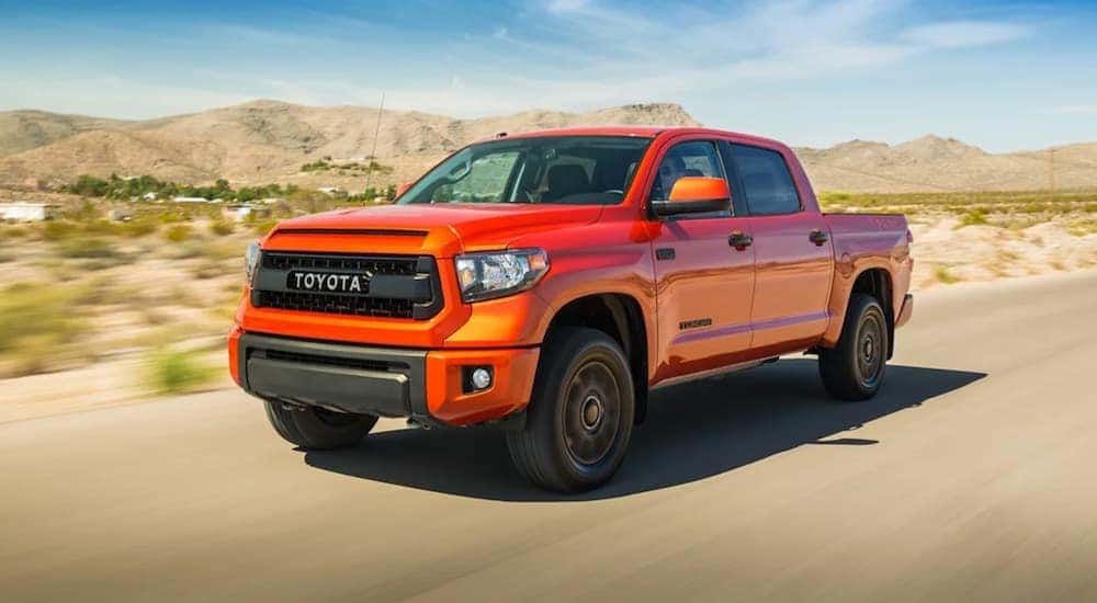 An orange 2015 Toyota Tundra is shown from the front at an angle while driving through the desert.