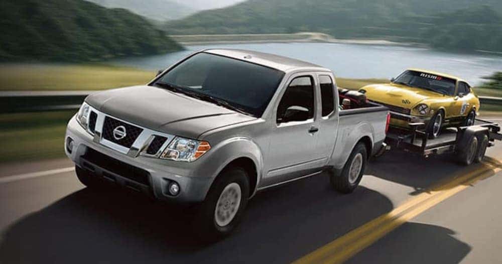 A silver 2020 Nissan Frontier is shown from the front at an angle while towing a car after leaving an Atlanta used truck dealer.