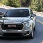 A grey 2022 GMC Terrain is shown from the front driving on an open road after leaving an Atlanta GMC dealer.