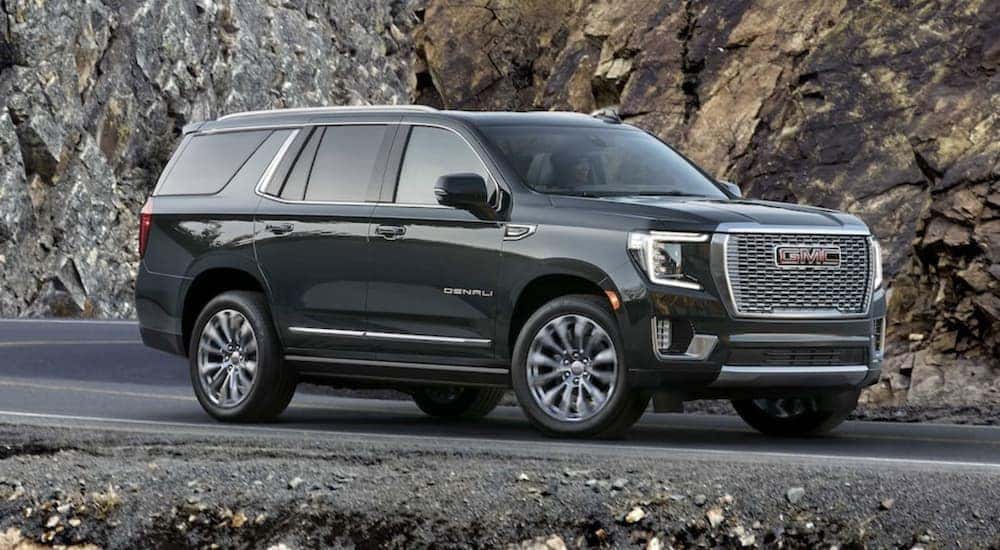 A black 2022 GMC Yukon is shown from the side driving on an open road.