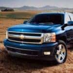 A blue 2007 Chevy Silverado 1500 is shown from the front at an angle while parked in a field.