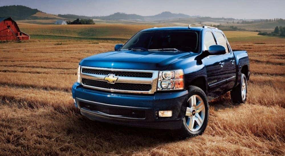 A blue 2007 Chevy Silverado 1500 is shown from the front at an angle while parked in a field.