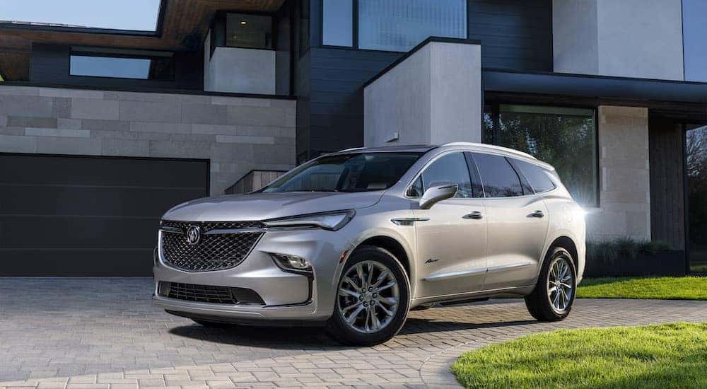 A silver 2022 Buick Enclave Avenir is shown from the front at an angle in front of a modern home.