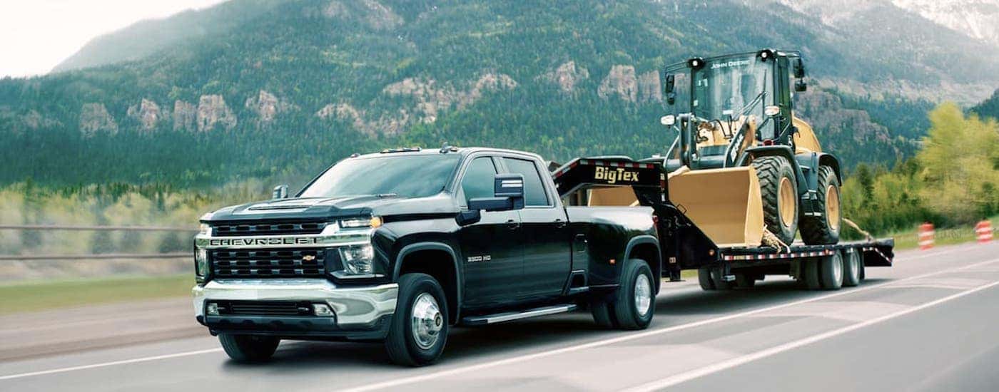 A black 2020 Chevy Silverado 3500 HD is shown from the front at an angle while towing equipment after leaving a dealer that had used diesel trucks for sale.