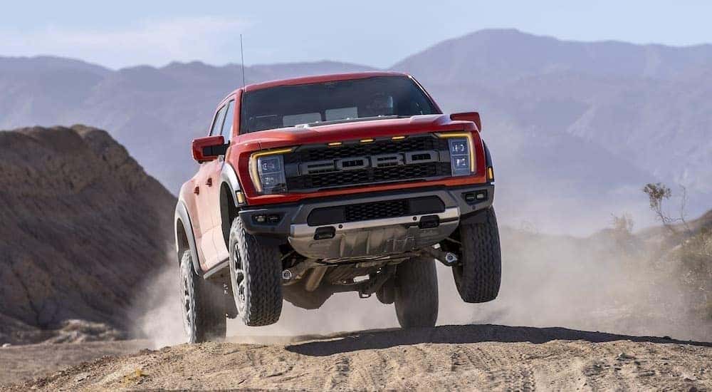 A red 2021 Ford F-150 Raptor is shown off-roading.