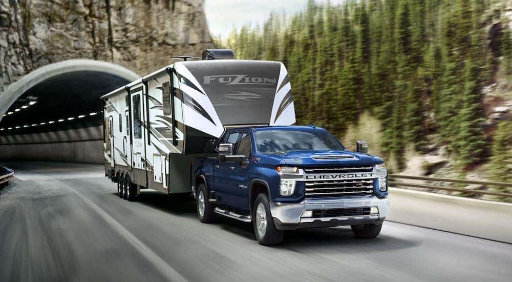 A blue Chevy 2022 Silverado 2500HD is shown towing a trailer.