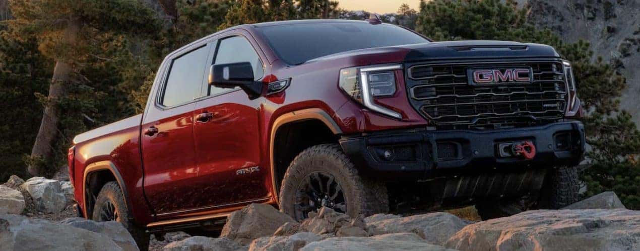 A red 2023 GMC Sierra 1500 AT4X is shown from the side parked on a rocky hill.