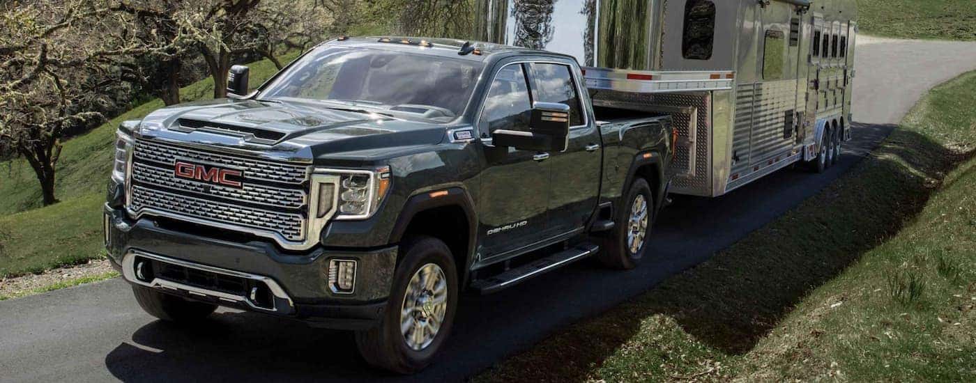 A black 2022 GMC Sierra 2500 HD is shown towing a closed trailer on an open road.