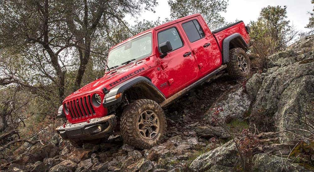 A red 2022 Jeep Gladiator Rubicon is shown off-roading on a steep rocky trail.