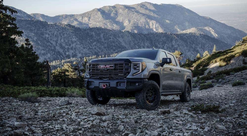 A grey 2023 GMC Sierra AT4X AEV is shown from the front at an angle after leaving a dealer that sells lifted GMC trucks.