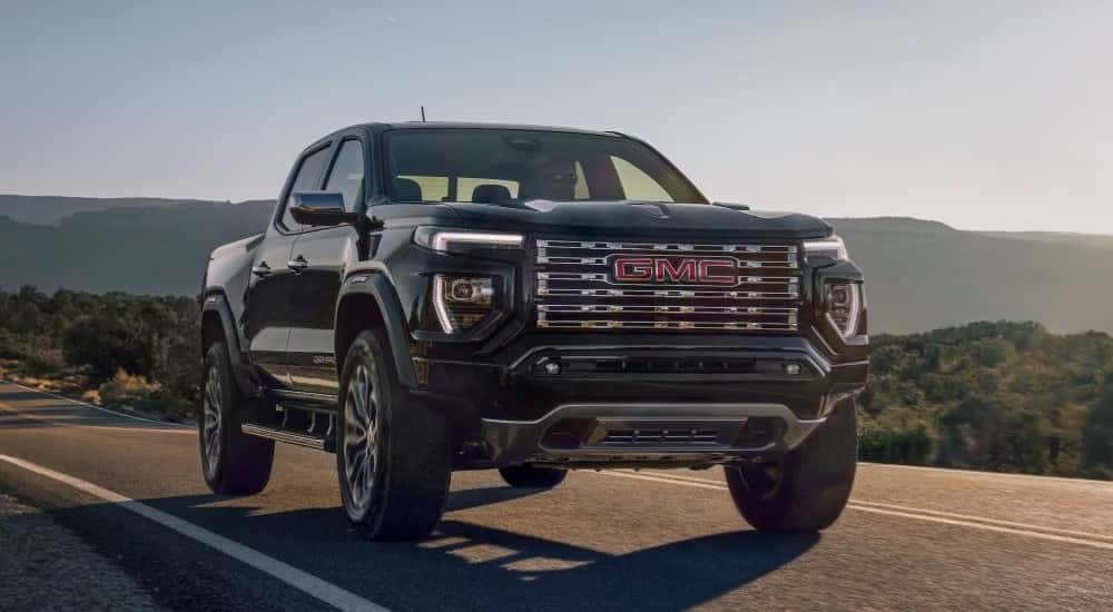 A black 2023 GMC Canyon Denali is shown driving on an open road.