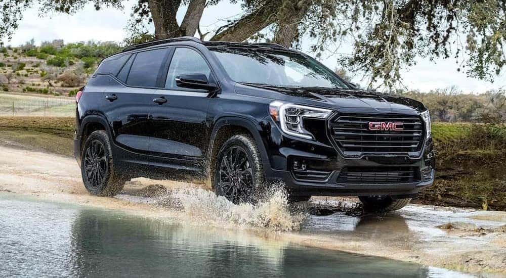 A black 2023 GMC Terrain is shown driving on a watered path.