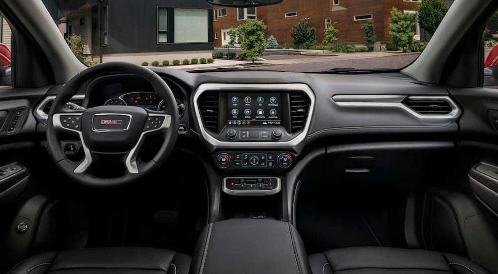 The black interior of a 2023 GMC Acadia SLT is shown from above the center console after leaving a dealer that has a GMC Acadia for sale.
