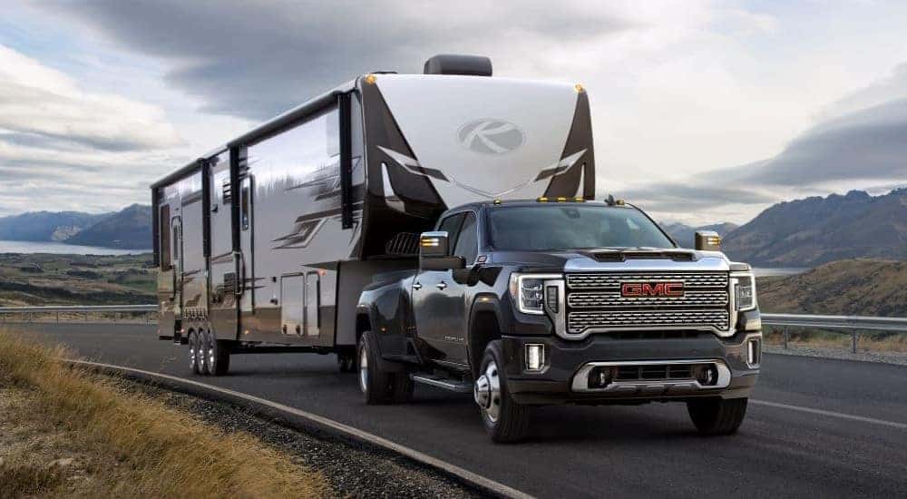 A black 2020 GMC Sierra 3500HD Denali is shown towing a camper trailer.