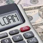 Calculator with"loan" written in screen sitting on top of money