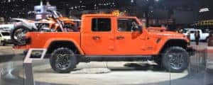 A bright orange Jeep Gladiator carrying an orange dirt bike in its truck bed.