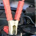 Charging battery car with jumper cables with red and black clamps