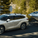 2020 Toyota Highlander towing a boat on lakeside road