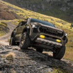 A Toyota Tacoma driving off-road on uneven and muddy terrain.