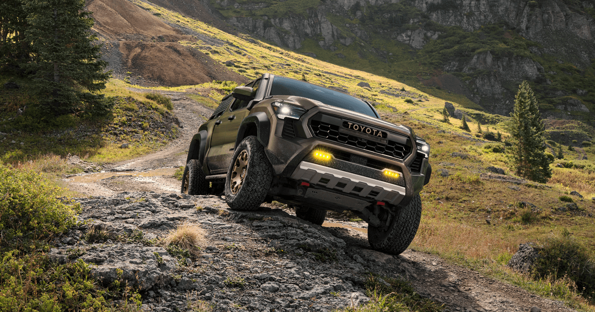 A Toyota Tacoma driving off-road on uneven and muddy terrain.