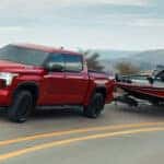 A red Toyota Tundra hauling a boat behind it on the road.