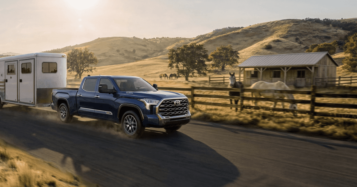 Toyota Tundra pulling a trailer on a country road next to a horse pasture