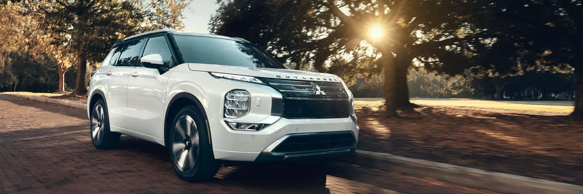 white 2026 mitsubishi outlander driving next to trees