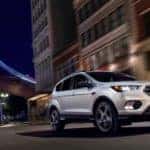 A white 2019 Ford Escape cruises a city street under a star filled sky