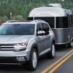 Silver Atlas towing a trailer down the road in front of a lake