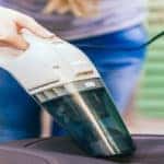 woman vacuuming inside of car