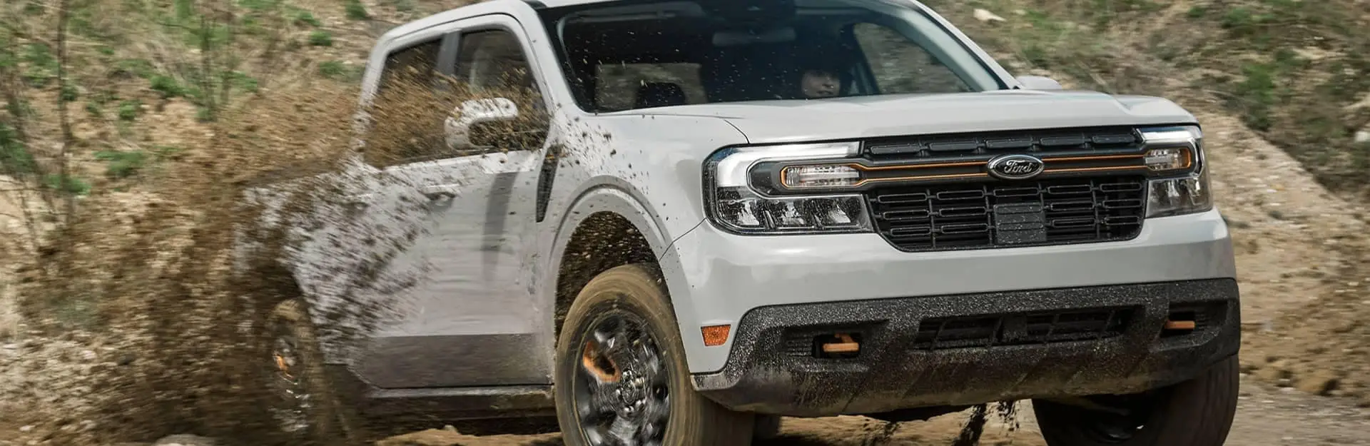 An exterior shot of a ford vehicle driving on a dirt road.